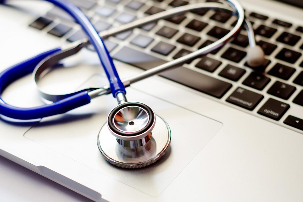 A stethoscope sitting on top of an Apple laptop.