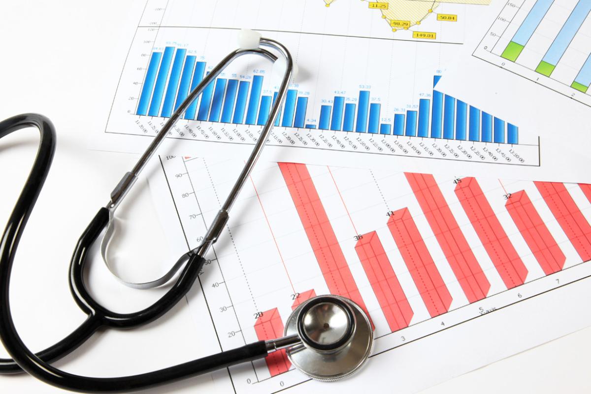 A stethoscope on top of various medical bar charts.