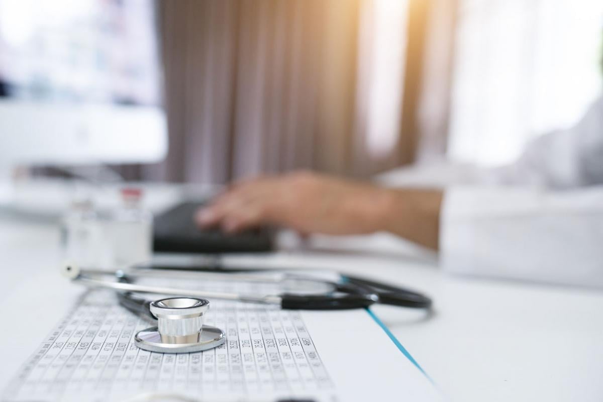 Stethoscope next to a physician working on a computer