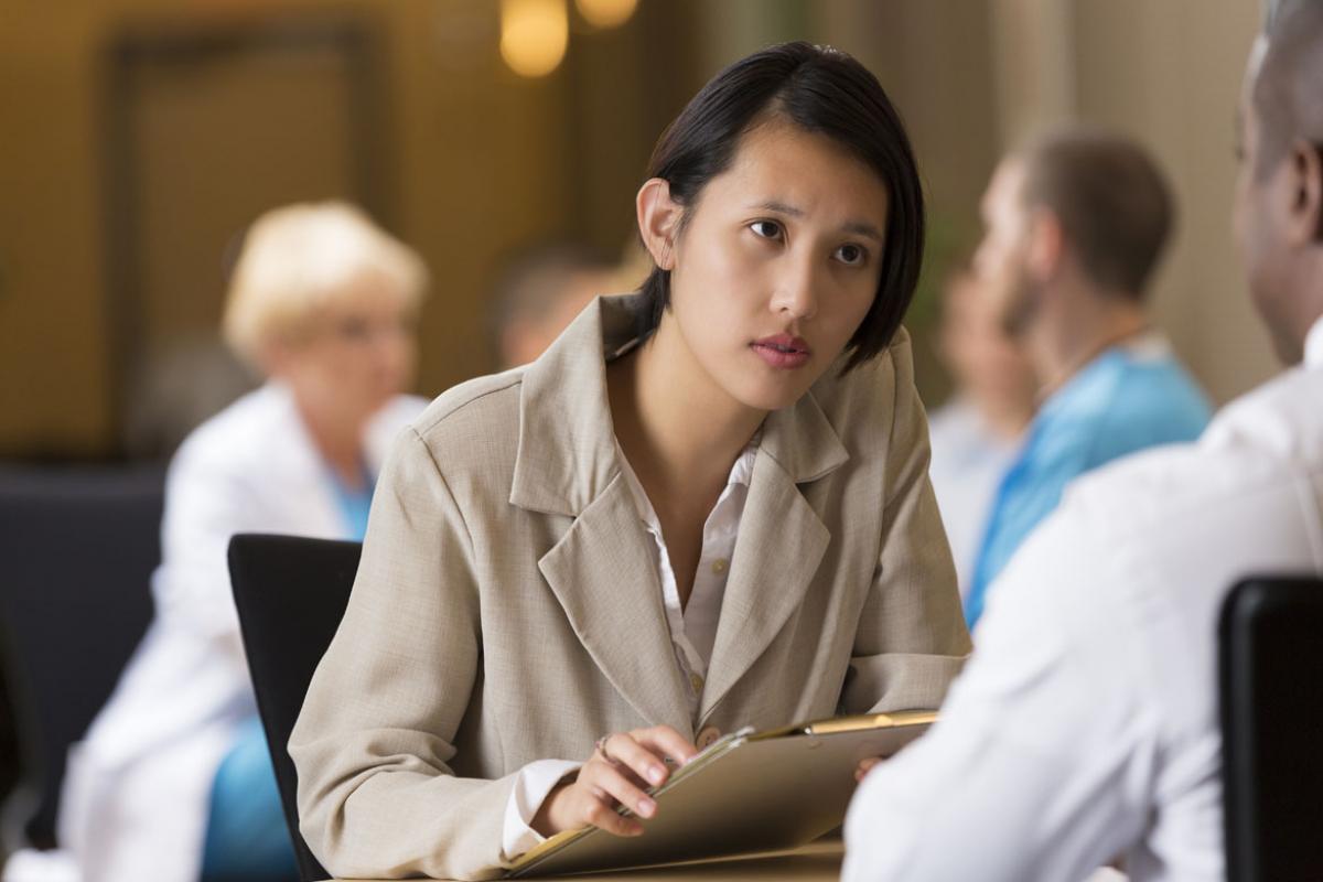 Woman with clipboard looking at man across the table 