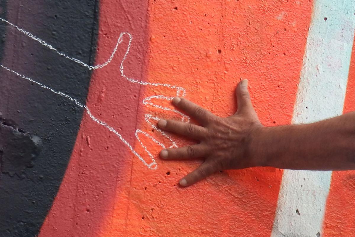 Human hand over a hand drawn with chalk