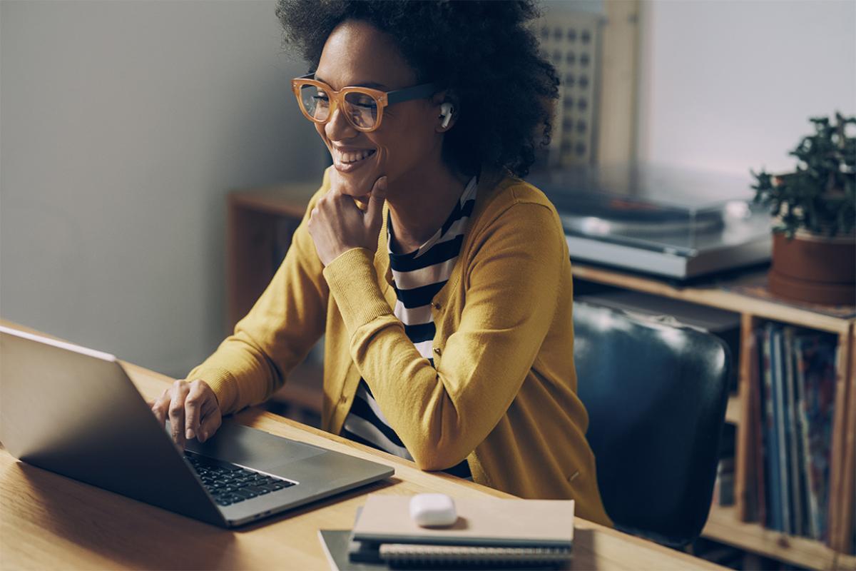  Smiling woman wearing glasses and listening to a presentation on a laptop