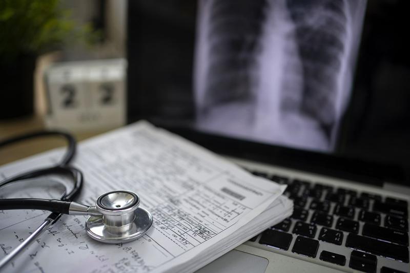 Stethoscope and stack of documents on a laptop computer