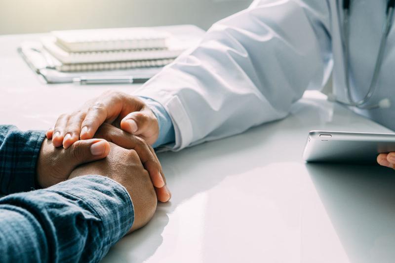 Physician placing their hand on a patient's hand