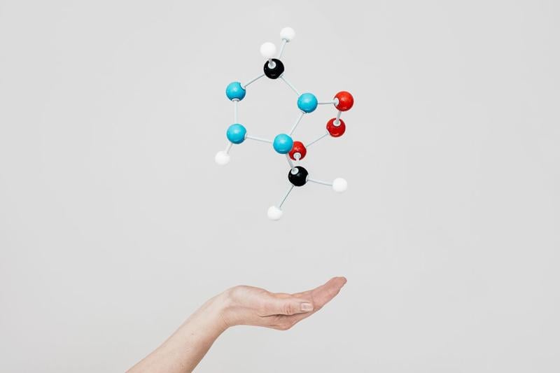 Model of molecules floating above person's hand