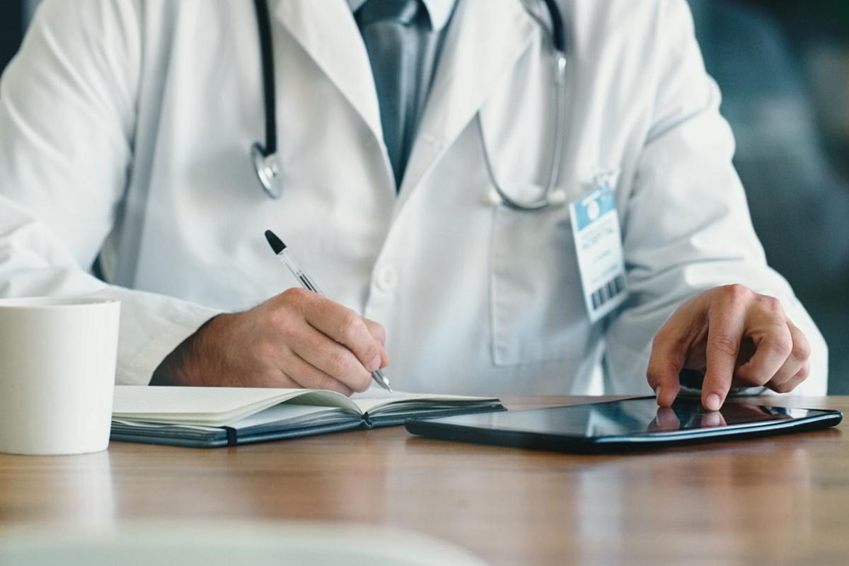 Physician writing and scrolling on a tablet