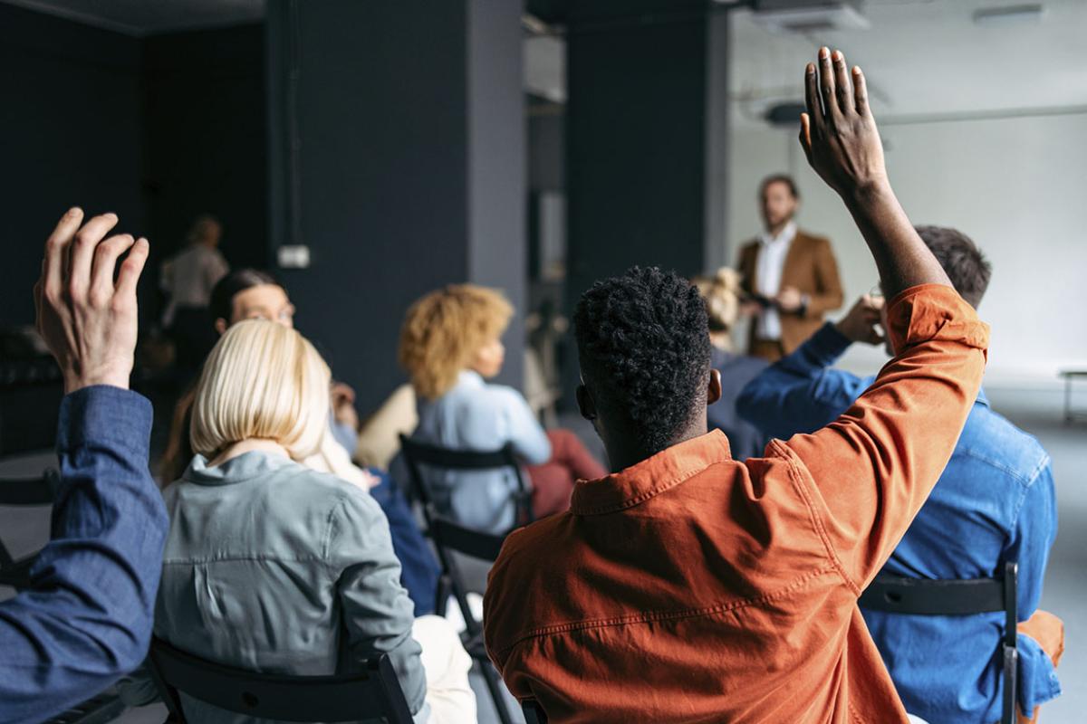 People in an audience with their hands raised