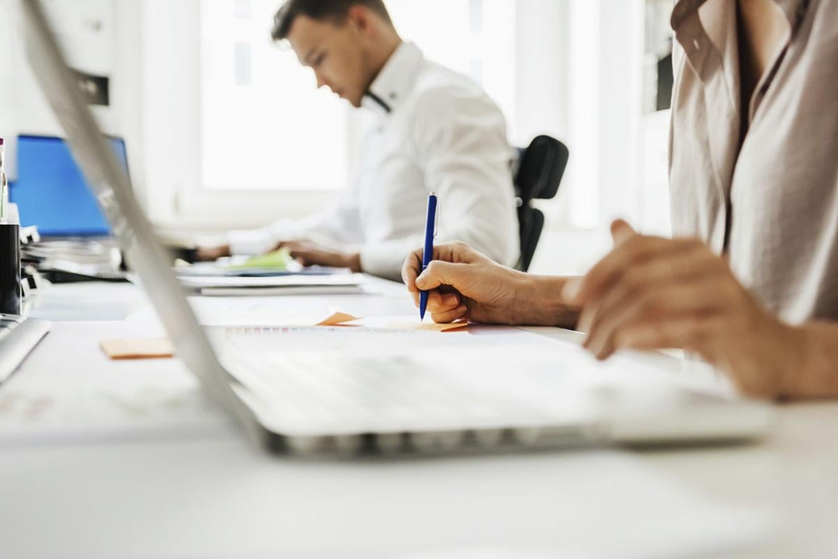 People sitting at a desk and using laptops while working at the office.