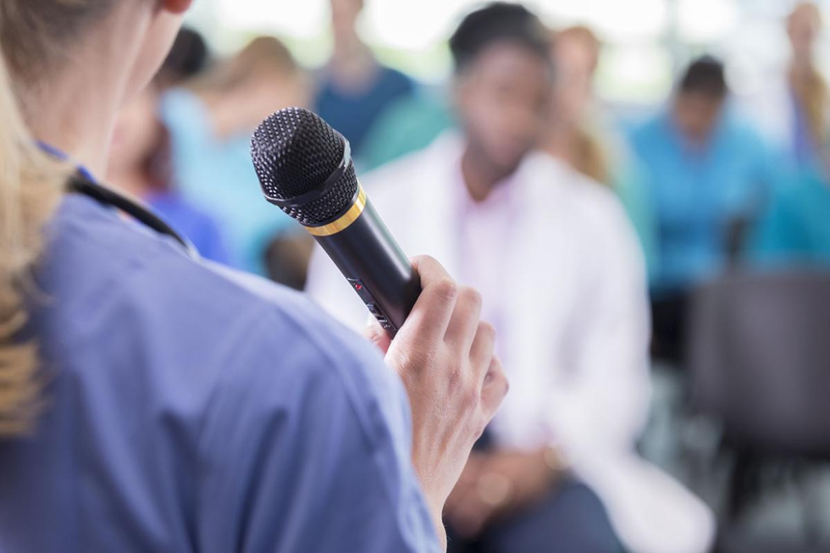 Person speaking into a microphone in front of a group