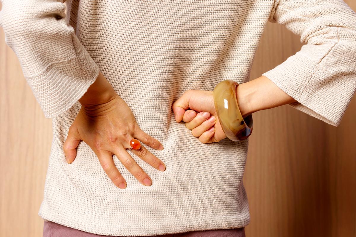 Woman with backache, massaging her back