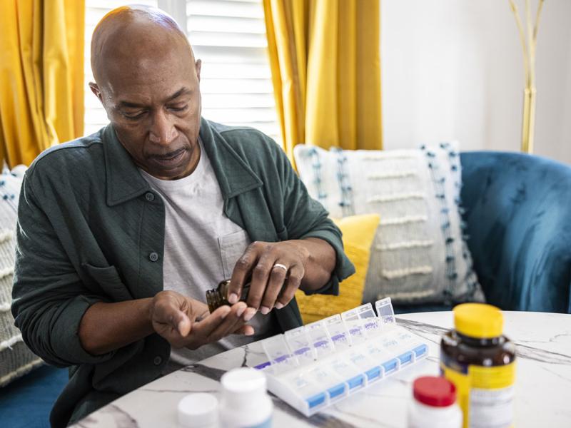 Senior man sorting prescription medications at kitchen table