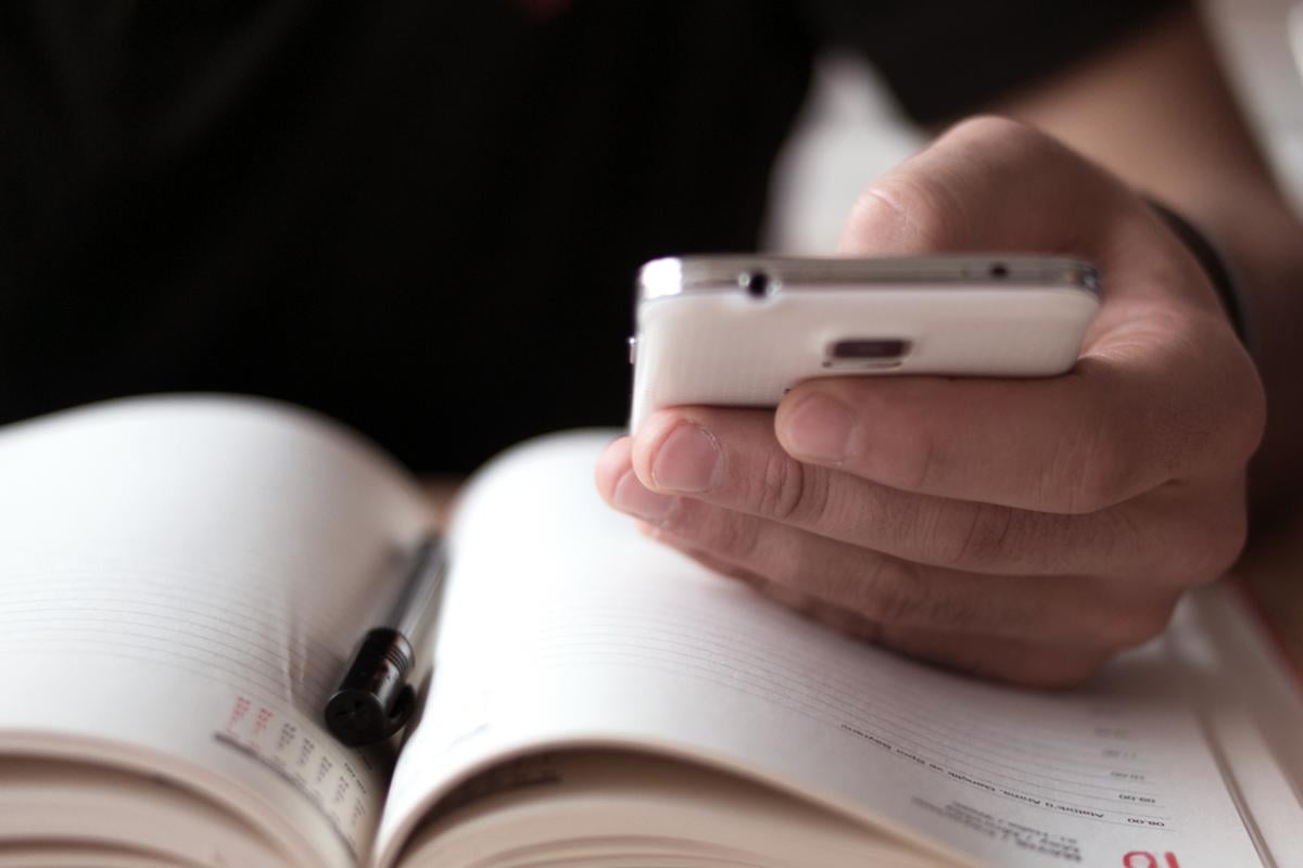 A physician checks his cell phone while using a calendar.