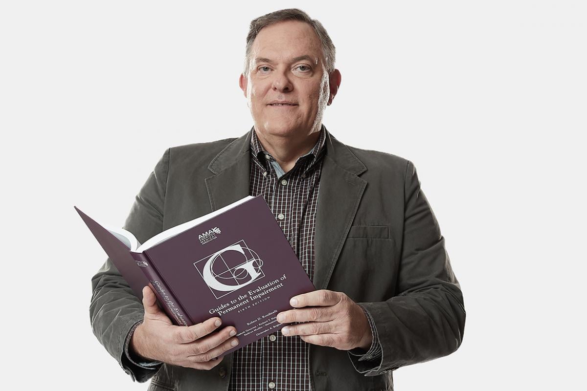 Doug Martin, MD, with AMA Guides book in his hand