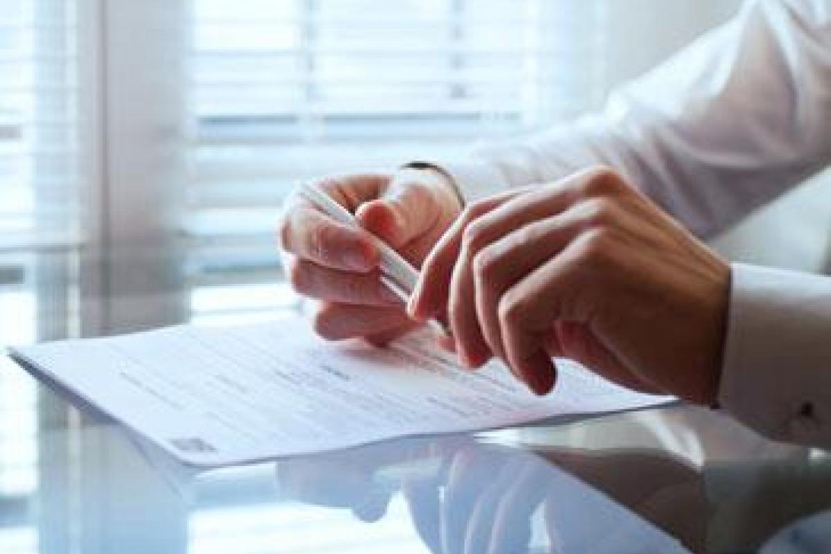 Man sitting with paperwork on desk.