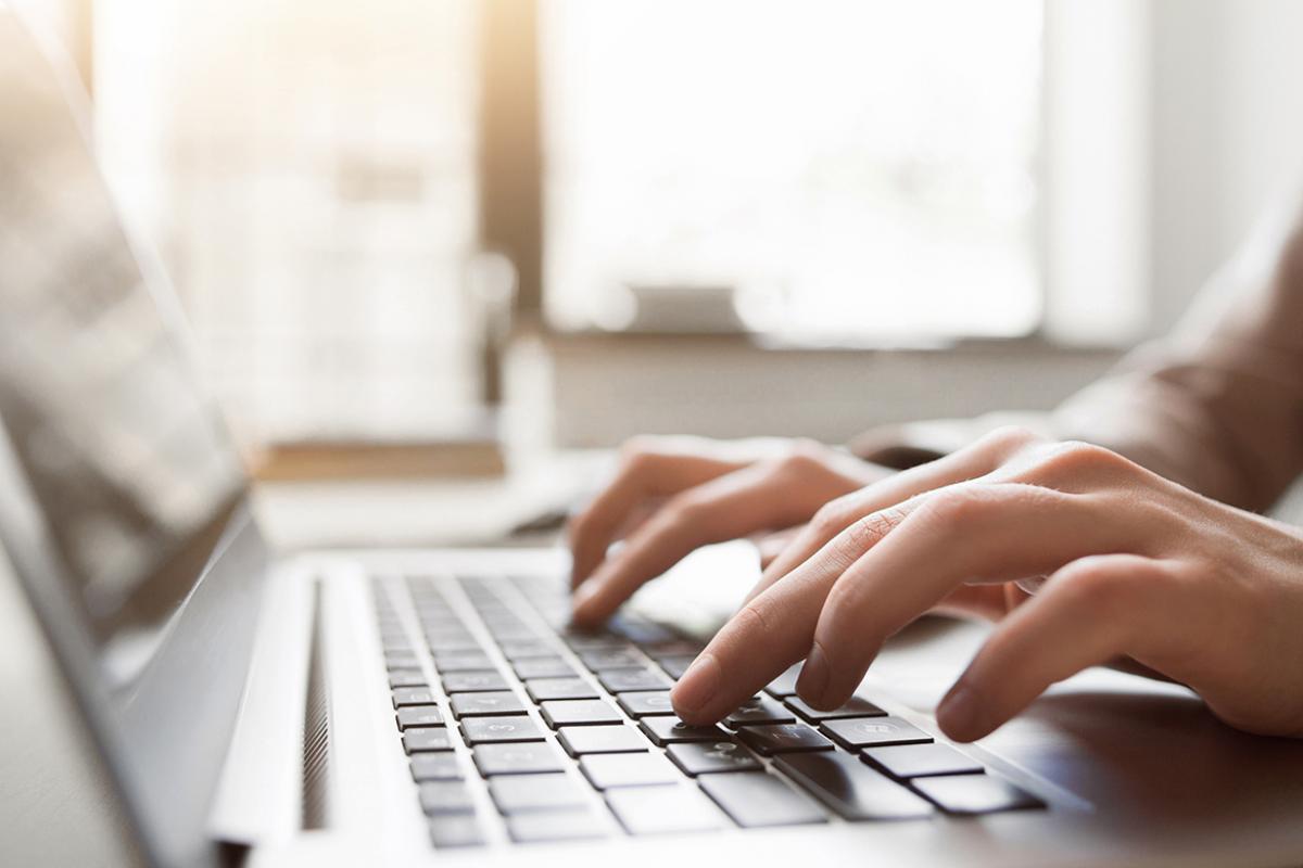 Close up of hands using a laptop.