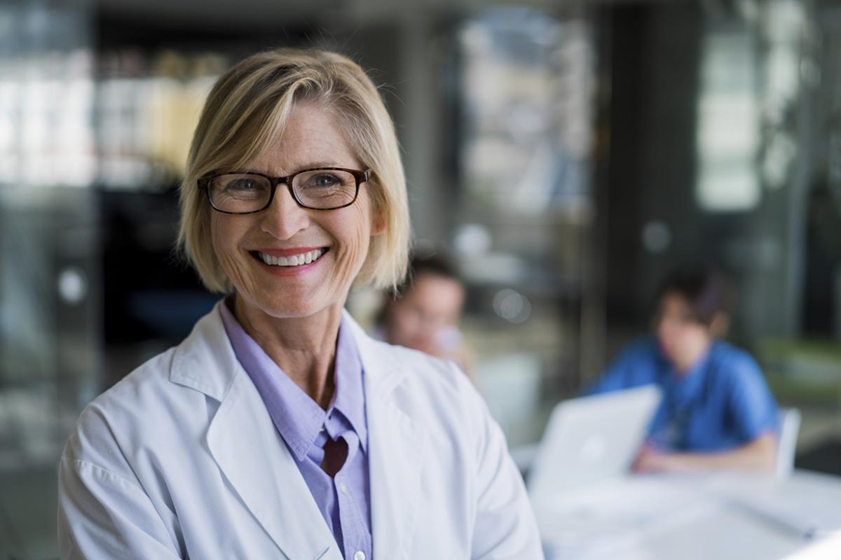 Portrait of a smiling female physician in a classroom setting.