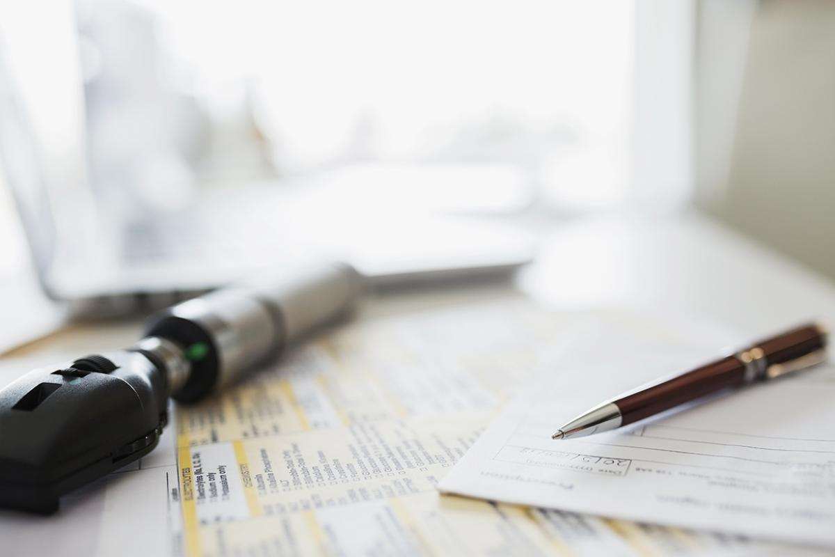 Physician's desk with otoscope and paperwork