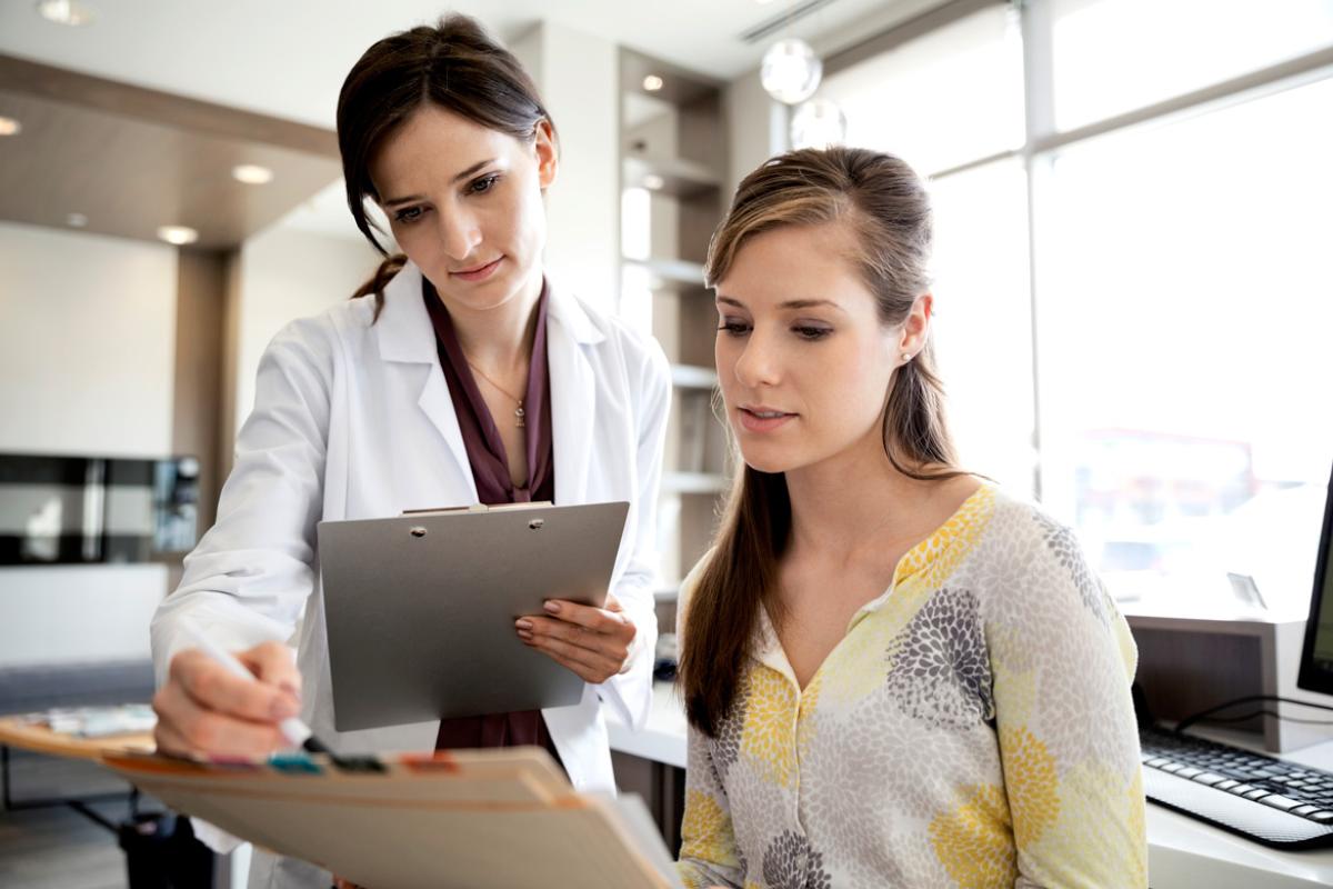 A young physician confers with her office manager about a coding question.