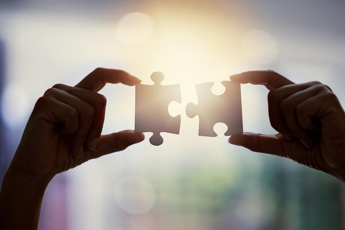 Hands holding two puzzle pieces